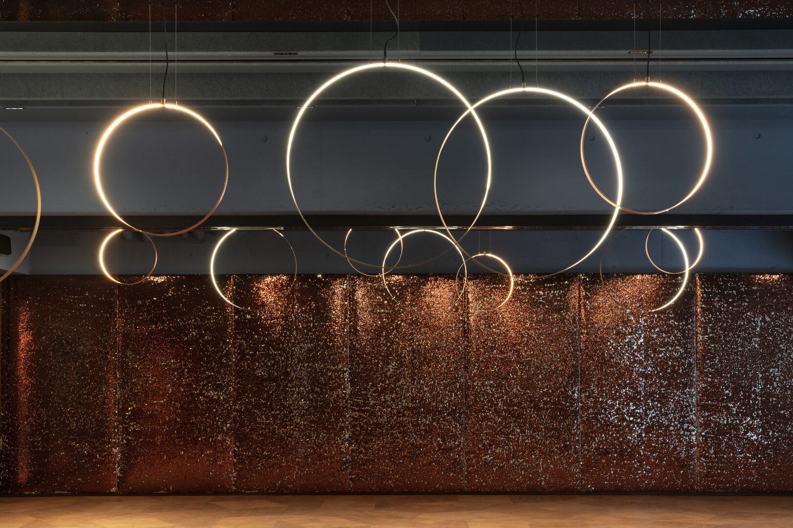 Seehotel Sonne Eich am Sempachersee: Atmosphärische Lichtgestaltung von 2F mit ringförmigen Pendelleuchten. Warmes Licht inszeniert Räume und greift das Sonnenkonzept architektonisch auf. Hochwertige Hotelbeleuchtung, eröffnet 2023.